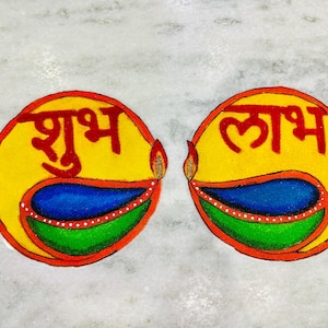 May include: Two circular, hand-drawn designs with the Hindi words "Shubh Labh" in red. Each design features a yellow background, a blue and green lamp, and a flame. The designs are on a white marble surface.