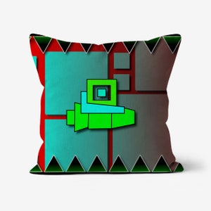 May include: A decorative pillow with a geometric design featuring a green, blue, and red spaceship-like shape on a teal and brown background. The pillow has a black and green border with a repeating triangle pattern.