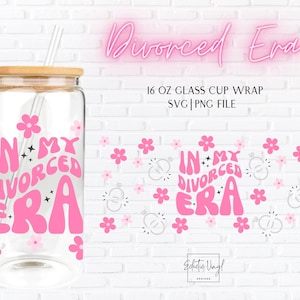 May include: A clear glass cup with a bamboo lid and a straw. The cup features the text "IN MY DIVORCED ERA" in pink, along with pink flower and star graphics. The words "Divorced Era" are written in pink script.