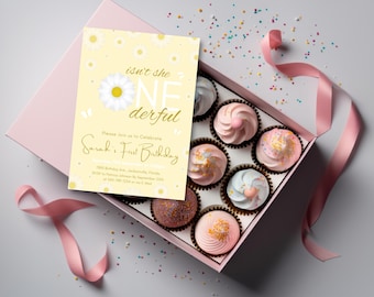 May include: A light pink box holds eight cupcakes with pastel frosting and sprinkles. A birthday invitation with a daisy design and the text "Isn't she ONE derful" is next to the box. A pink ribbon and confetti complete the scene.