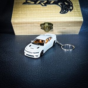 May include: White Dodge Charger SRT keychain with a silver key ring. The keychain is a miniature replica of the car and has a detailed interior.