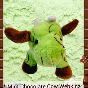 May include: A plush cow toy featuring a light green body with dark brown ears and hooves, small white horns, and black eyes. The toy has a soft, fuzzy texture and is positioned against a textured light green background with the text Mint Chocolate Cow Webkinz.