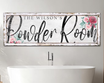 May include: White wooden sign with distressed edges and a black floral design. The sign reads "The Wilson's Powder Room".