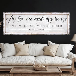 Puede incluir: Un letrero de madera blanco con texto negro que dice "As for me and my house we will serve the Lord - Joshua 24:15". El letrero está colgado en una pared negra sobre un sofá blanco.
