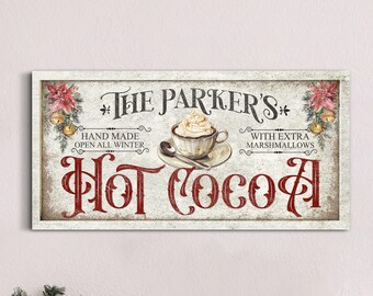Op de afbeelding: Een vintage-stijl bord met de tekst "The Parker's* Hot Cocoa*" in rode letters. Het bord toont een kopje warme chocolademelk met slagroom en een lepel, en de tekst "Hand Made Open All Winter" en "With Extra Marshmallows".