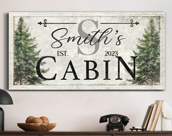 May include: A rustic wooden sign with a distressed white background featuring the text "Smith's Cabin Est. 2023" with a stylized letter "S" and two green pine trees on either side.