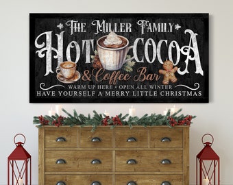 Op de afbeelding: Een zwart krijtbord met witte letters waarop staat "The Miller Family Hot Cocoa & Coffee Bar". Het bord toont ook een peperkoekman, een kopje warme chocolademelk met slagroom en een kopje koffie. De tekst onder de hoofdtitel luidt "Warm je hier op. De hele winter open. Fijne Kerst."