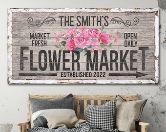 May include: A rustic wooden sign with white paint and a floral design. The sign reads "The Smith's Flower Market Established 2022" with the words "Market Fresh" and "Open Daily" on either side of the floral design.