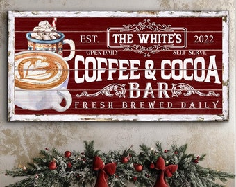 Op de afbeelding: Een rood houten bord met witte letters waarop staat "EST. THE WHITE'S 2022 OPEN DAILY SELF SERVE COFFEE & COCOA BAR FRESH BREWED DAILY". Het bord heeft een verweerde uitstraling en toont een cartoonafbeelding van een kopje koffie en een kopje warme chocolademelk met marshmallows.