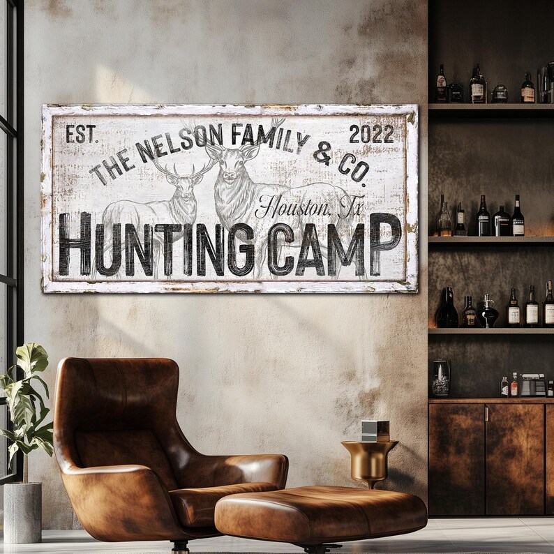 May include: White wooden sign with black text that reads "EST. THE NELSON FAMILY & CO. Houston, Tx HUNTING CAMP 2022". The sign features a drawing of two deer.