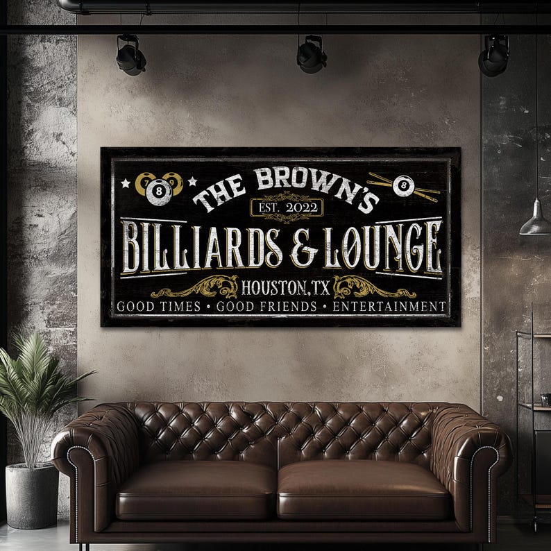May include: A black and white sign with gold accents that reads "The Brown's Billiards & Lounge, Est. 2022, Houston, TX, Good Times, Good Friends, Entertainment". The sign features two billiard balls and crossed pool cues.