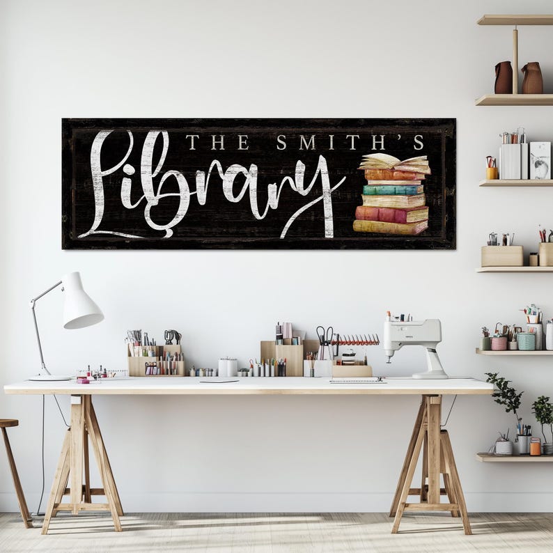 Op de afbeelding: Een zwart-wit bord met de tekst "The Smith's Library" in witte schrijfletters. Rechts op het bord ligt een stapel kleurrijke boeken met een open boek bovenop.
