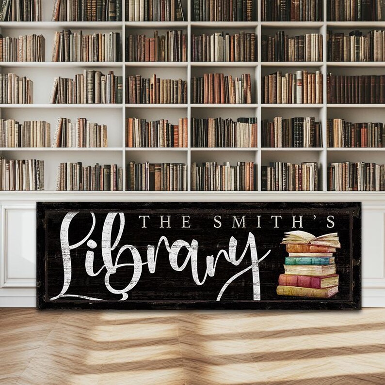 Op de afbeelding: Een zwart houten bord met witte tekst dat "The Smith's Library" zegt. Rechts van het bord staat een stapel vintage boeken met een open boek bovenop.
