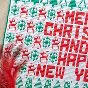 May include: White crochet fabric with a red and green Christmas design. The design features reindeer, snowflakes, and the words "Merry Christmas and Happy New Year".