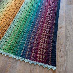 May include: A handmade crochet shawl with a gradient of colors, transitioning from gold to green, blue, and deep red. The shawl features an openwork design with a scalloped edge, perfect for a cozy accessory.