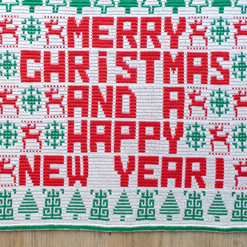 May include: White crochet blanket with a red and green Christmas design. The blanket features the text "Merry Christmas and a Happy New Year!"