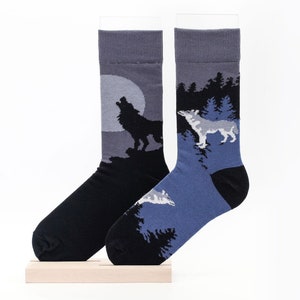 May include: A pair of grey and blue socks with a wolf howling at the moon on one sock and a wolf walking through a forest on the other sock.