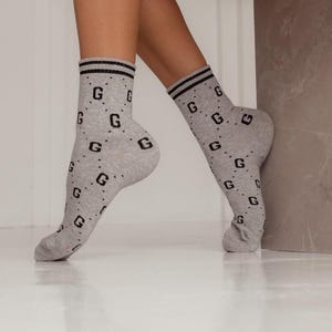 May include: A pair of grey ankle socks with a black "G" pattern.