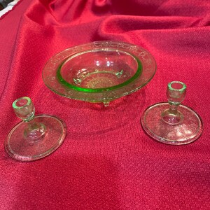 May include: Three pieces of green Depression glass: a small bowl with a scalloped edge and two candle holders. The bowl and candle holders have a textured, frosted finish.