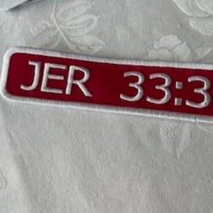 Könnte beinhalten: Roter rechteckiger Patch mit weißem Text, der "JER 33:3" lautet.
