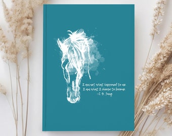 May include: Teal blue notebook with a white watercolor illustration of a horse's head and the quote "I am not what happened to me. I am what I choose to become. - C.G. Jung."