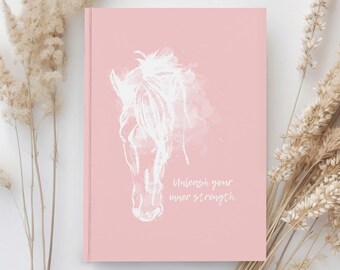 May include: A pink notebook with a white watercolor illustration of a horse's head and the text "Unleash your inner strength."