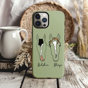 Puede incluir: Una funda de tel&eacute;fono verde con una ilustraci&oacute;n de cabeza de caballo blanca y marr&oacute;n a cada lado. El texto "Bolshoi" y "Blaze" est&aacute; impreso debajo de cada cabeza de caballo.