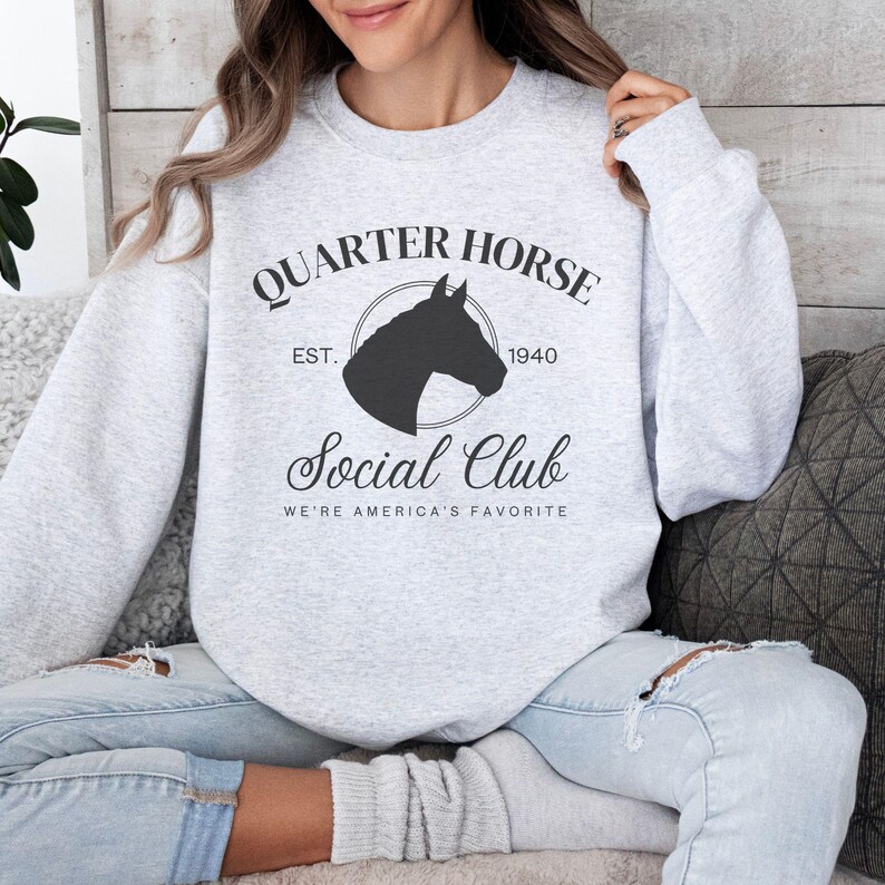 May include: A gray sweatshirt with a black silhouette of a horse's head in a circle. The text "Quarter Horse Social Club Est. 1940 We're America's Favorite" is printed on the sweatshirt.
