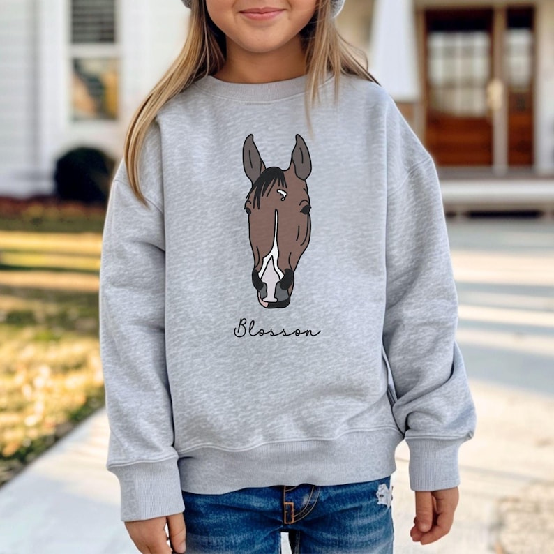 May include: A gray sweatshirt with a brown horse head illustration and the word "Blossom" printed below it.