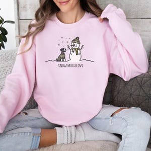 May include: Pink sweatshirt with a snowman and a dog graphic. The text "Snow Much Love" is printed below the graphic.