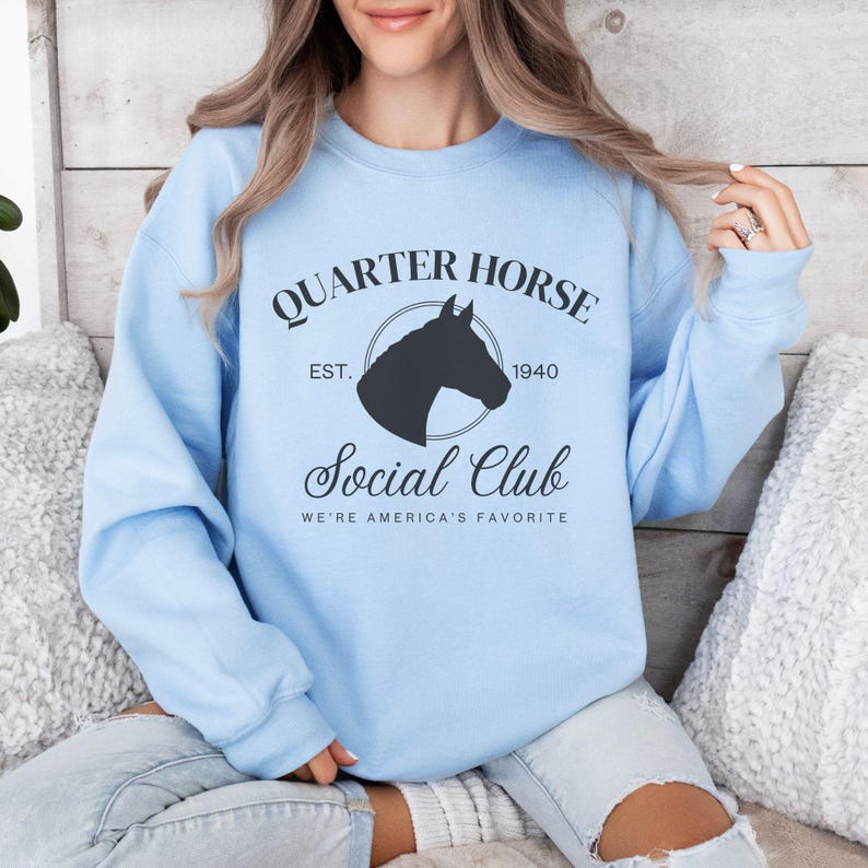 May include: Light blue sweatshirt with a black graphic of a horse's head in a circle with the text "Quarter Horse Social Club Est. 1940 We're America's Favorite"