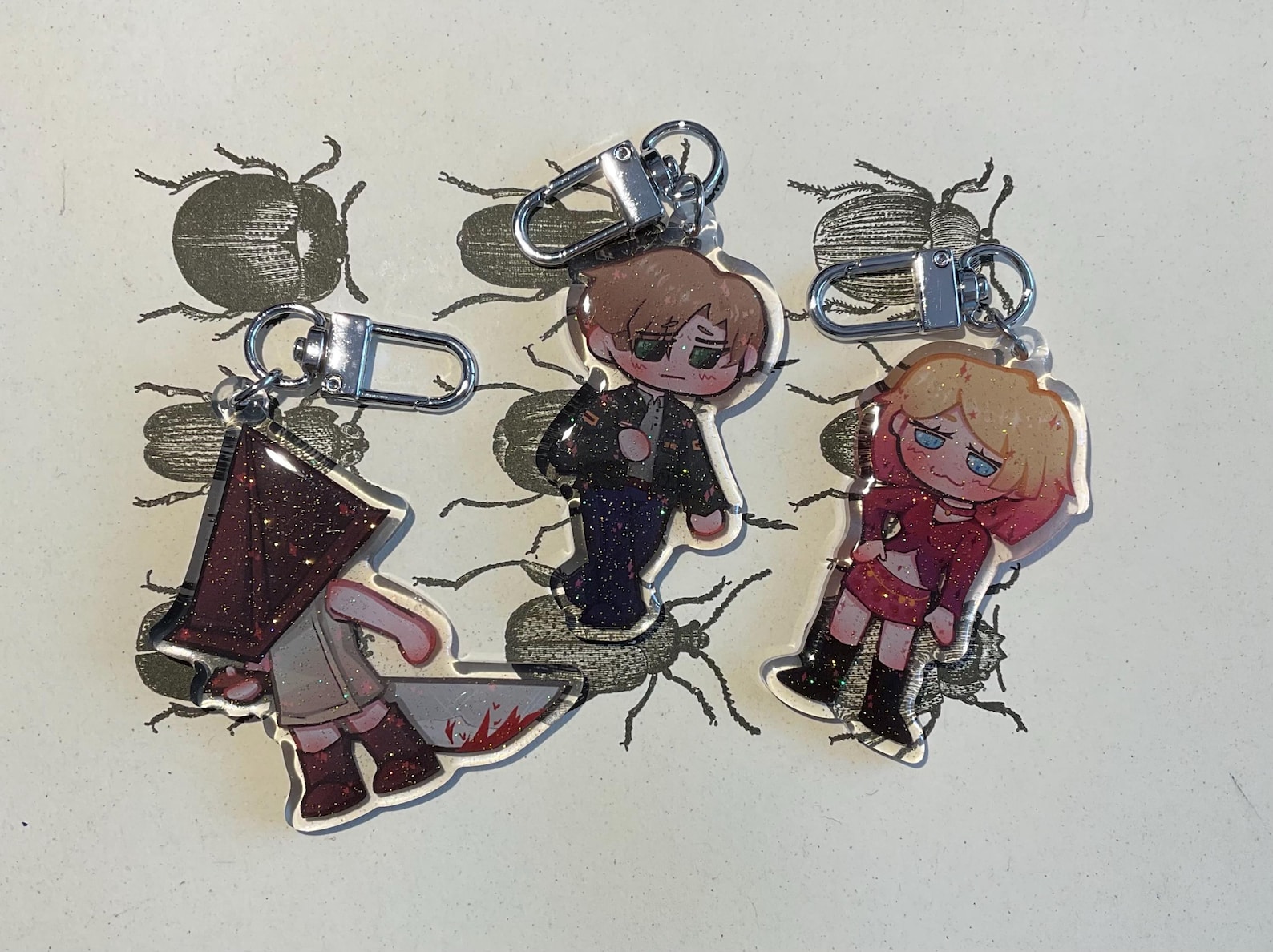 Portachiavi in resina epossidica glitterata Silent Hill 2: Maria, James Sunderland, Pyramid Head (63,5 mm)