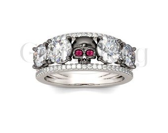May include: A black skull ring with red eyes and four round clear stones set in a silver band.