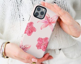 Puede incluir: Una funda de teléfono rosa con un diseño floral. La funda presenta flores y hojas rosas sobre un fondo blanco. La funda de teléfono está diseñada para un iPhone con una protuberancia de cámara.