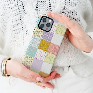 May include: A colorful phone case with a patchwork design featuring various floral patterns and colors, including pink, blue, yellow, and green.