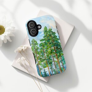 May include: A phone case featuring a watercolor painting of tall green pine trees against a blue sky with clouds. The case has a black border and covers the back and sides of the phone. The design evokes a nature theme.