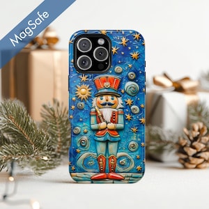 May include: A blue phone case featuring a nutcracker design. The case has a detailed illustration of a nutcracker soldier with a red and orange hat and jacket, surrounded by stars and swirls. The word "MagSafe" is printed on the top left.
