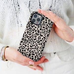 May include: A beige and black leopard print phone case for an iPhone.