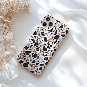May include: A white phone case with a repeating pattern of black cow spots and watercolor-style cow faces. The case has a glossy finish and is designed to fit a smartphone.