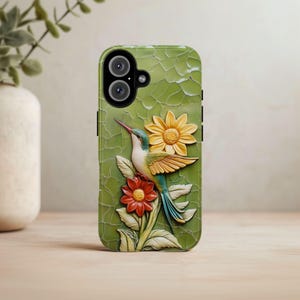 May include: A green phone case with a 3D hummingbird and flowers. The hummingbird is green, blue, and yellow. The flowers are yellow and red.