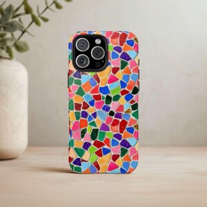May include: A colorful phone case with a mosaic pattern. The case is made of a durable material and has a raised lip to protect the screen.