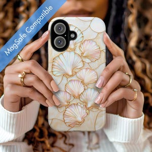 May include: A white phone case featuring a design of gold and white seashells. The case is compatible with MagSafe.