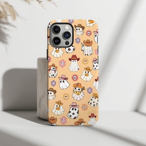Puede incluir: Una funda de teléfono con un patrón de fantasmas con sombreros de vaquero y flores sobre un fondo naranja claro.