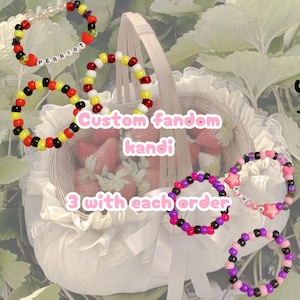 May include: Five circular bracelets made of colorful plastic pony beads. Two bracelets feature white letter beads spelling PERRIOT and ASHLEY, while others include star and heart-shaped charms in red, pink, yellow, black, and purple.