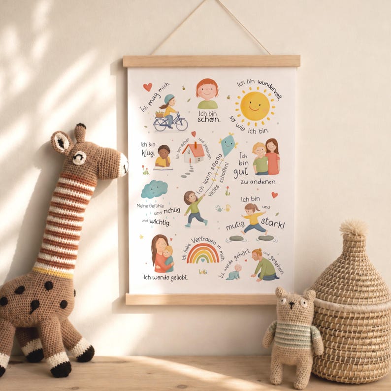 May include: A framed poster with a wooden hanger displays colorful illustrations and German text. The artwork features children, a sun, a rainbow, and other cheerful images. A crocheted giraffe, a bear, and a woven basket are in the foreground.