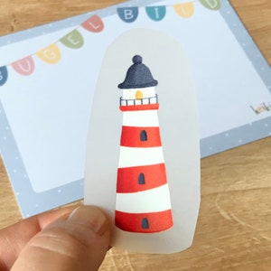 Könnte beinhalten: Ein rot-weiß gestreifter Leuchtturm mit schwarzem Dach und gelbem Licht. Der Leuchtturm befindet sich auf einem transparenten Hintergrund.