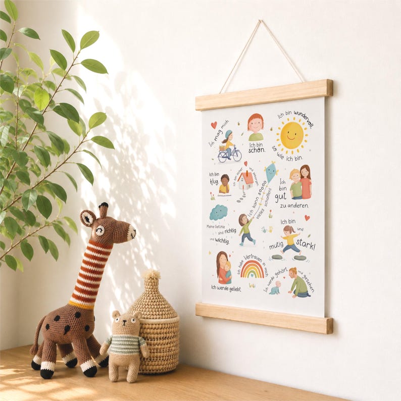 May include: A children's wall art print with a wooden frame and a string for hanging. The print features colorful illustrations and German text. A crocheted giraffe, bear, and basket are in the foreground.