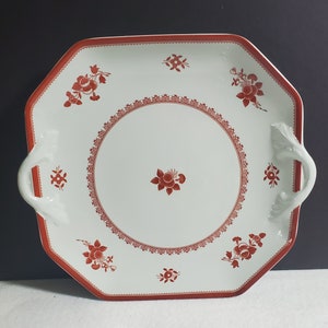 May include: A white octagonal serving platter with two handles. The platter has a red floral design around the edge and in the center.