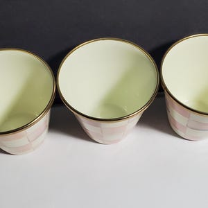 May include: Three conical cups with a cream-colored interior and a gold-toned rim. The exterior features a repeating checkered pattern in alternating shades of soft pink and white, creating a consistent design across all three drinking vessels.