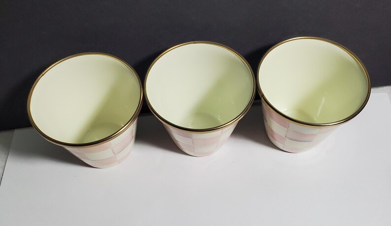 May include: Three conical cups with a cream-colored interior and a gold-toned rim. The exterior features a repeating checkered pattern in alternating shades of soft pink and white, creating a consistent design across all three drinking vessels.